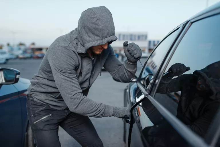 Homem roubando um carro. E como o seguro contra roubo e furto podem te ajudar.